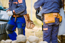 Close up of two construction workers with tool bags